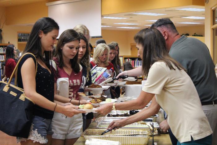 Principal+Susan+Atherley+passes+out+food+during+Senior+BBQ+day.+Seniors+came+to+school+for+one+last+day+to+spend+it+eating+BBQ+in+the+media+center.