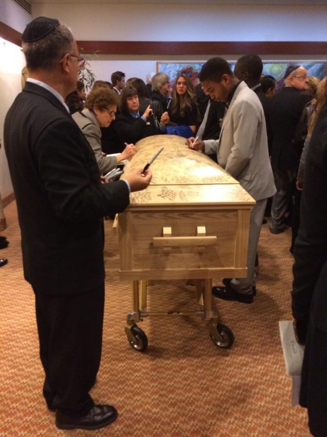 Friends and family sign the coffins of Alex and Jackie Berman as their final form of reverence.