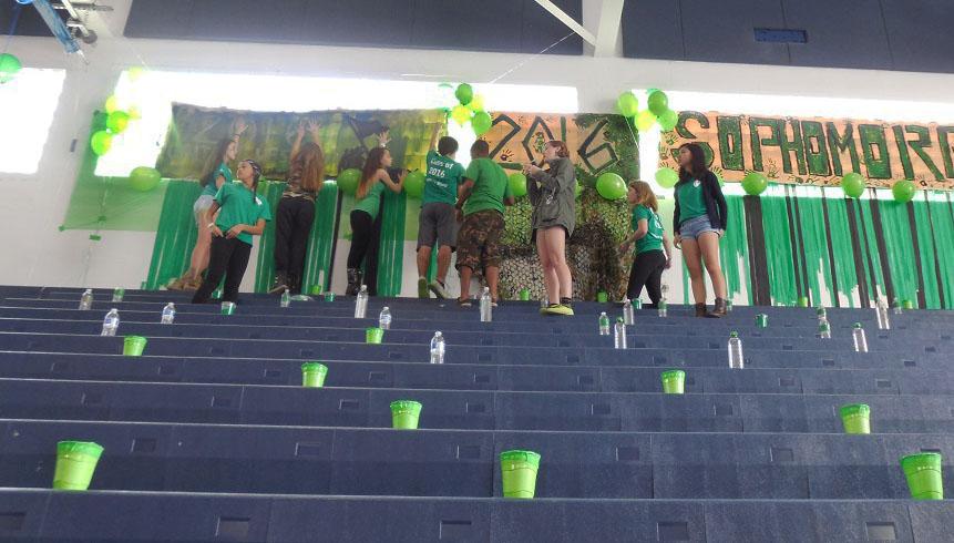 Digital media sophomore Valentina Suarez (left), communications sophomore Michelle
Birch, visual sophomore Frances Landrum, digital media sophomores Victoria Morejon,
Spencer Altus, Madelyn Winchester, band sophomore Molly Lynch and keyboard sophomore
Catherine Zeng hang up their army-themed banner while preparing the sophomore section.