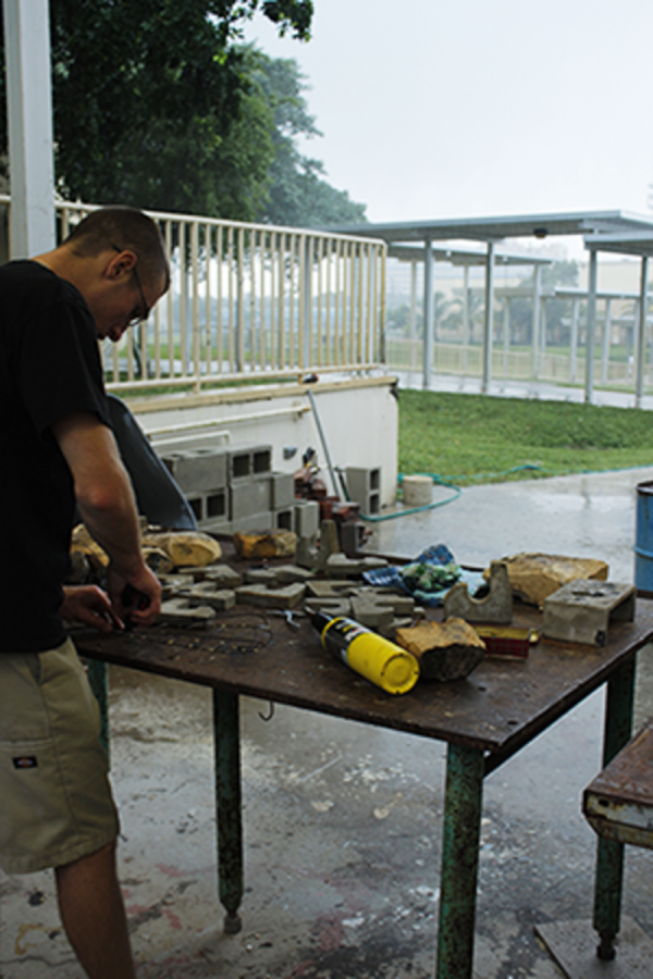 Visual junior Jacob Cartales welds an art piece, despite the rainy weather.