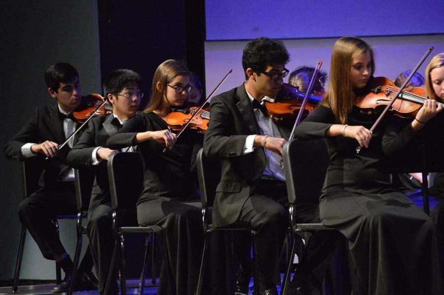  Strings seniors Felipe Bomeny, Taisuke Yasudam, Robin Tozzie, strings junior Yuri Santos  and strings senior Rebecca Tozzie play in the violin section during the concert. 