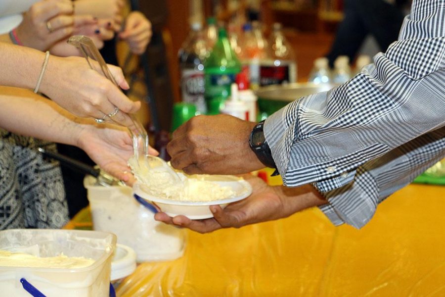 Communications senior and CHS officer Jordan McCrary (l-r) serves vanilla ice cream from the ice cream bar to Dr. Ancil Deluz during the CHS induction.