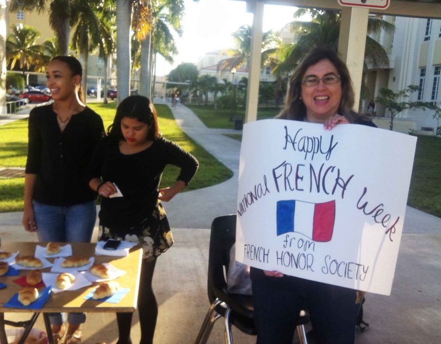 French teacher Linda  Kass  and members of the French Honor Society hand out free croissants at the bus loop Friday morning.