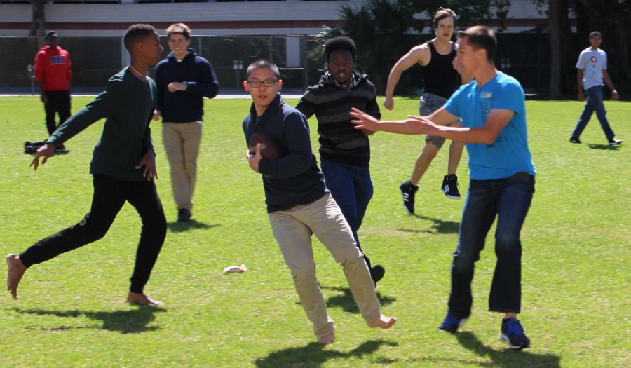 (L-R) Visual sophomore Aaron Nisbett, band junior Amari Greene and band sophomore Camden Laparche chase piano senior Andy Yang (center) in a friendly game of two-hand touch football during lunch.
