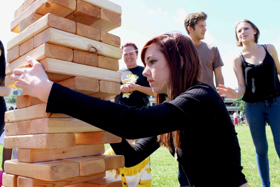 Vocal+junior+Nicole+Kelly+carefully+removes+a+block+in+a+game+of+writer%E2%80%99s+Jenga.+Each+block+has+a+word+taped+on+it%2C+and+the+first+team+to+form+a+sentence+wins+the+game.+Writer%E2%80%99s+Jenga+and+other+field+games+were+played+at+the+creative+writing+class+Writers+Block+Party.+