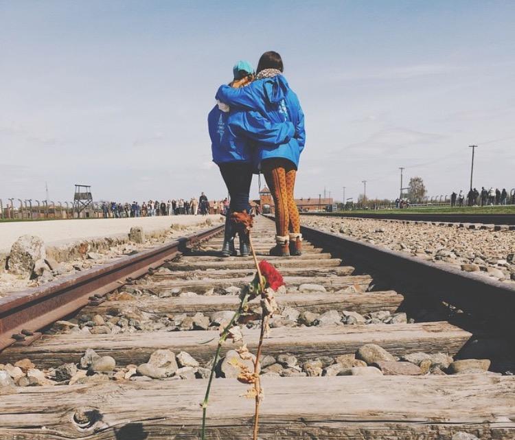 Theatre senior Amanda Shore (left) walks over the train tracks that marked the lives lost during the holocaust.