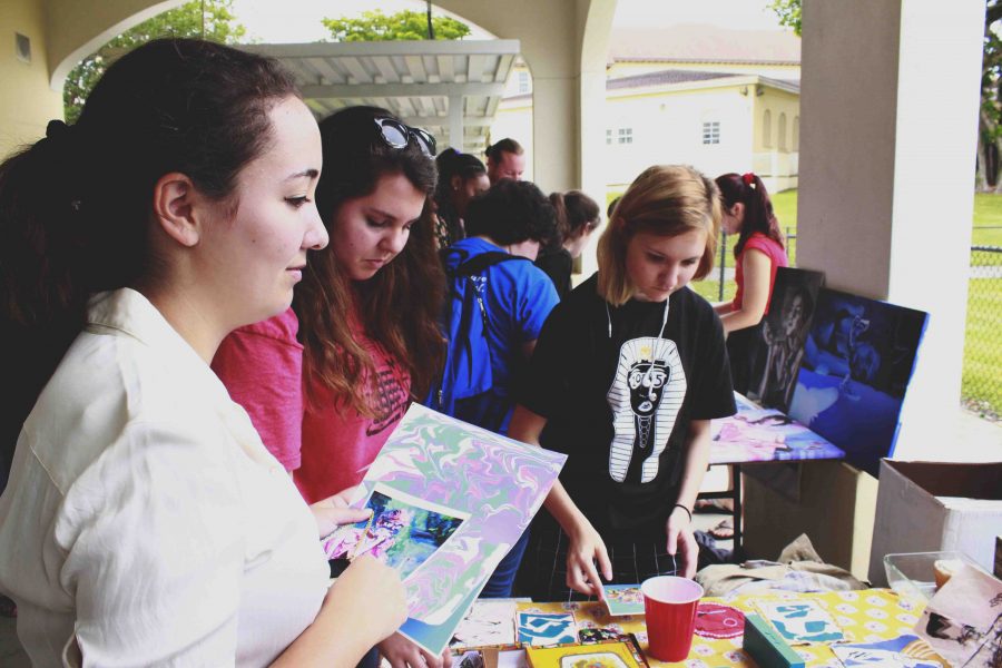 (L-R) Communications juniors Amanda Goodman and Lauren Punales look over communication senior Julianne Mink Ratcliffs booth at the senior art sale at lunch. This will be the last art sale before the senior sign out on Wednesday, May 6. 