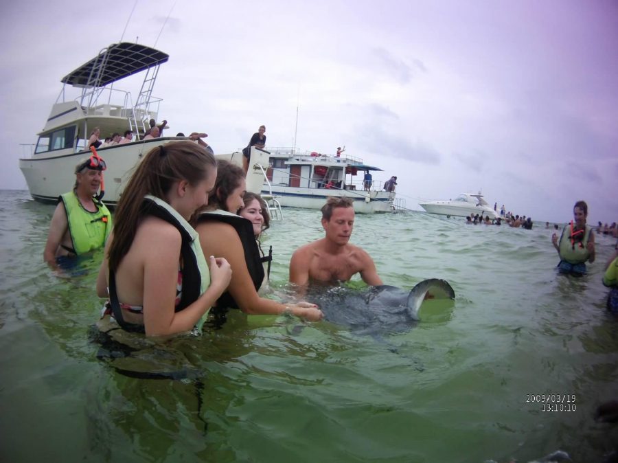 Communications junior Alana Gomez (middle) stands with two of her friends in the Caribbean Ocean as they are greeted by sting rays.