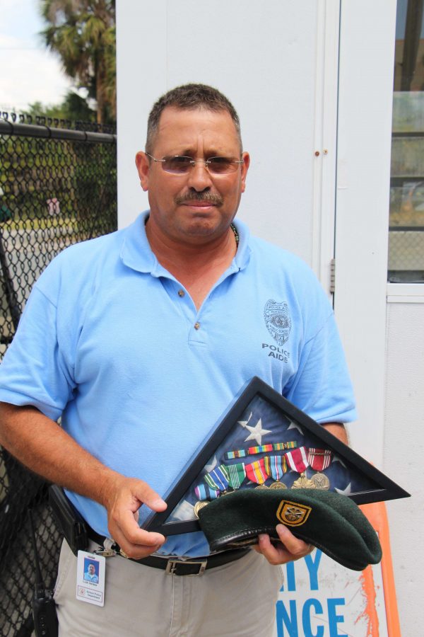 Officer Louis Valdez stands with medals he has received throughout his military service.