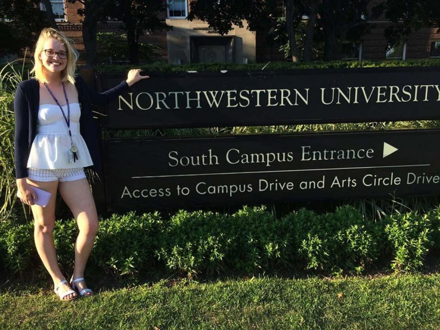 Communications junior Rhodes Evans stands alongside a campus entrance sign on the Northwestern University campus. 