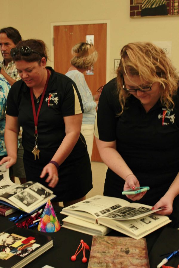 Social studies teacher Sarah Ray and visual arts teacher Lacey Van Reeth look at yearbooks from previous years. All the yearbooks since the first graduating class of 1990 were on display for students and faculty .