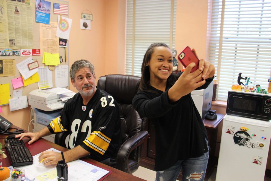 Communications+senior+Michelle+Birch+takes+a+selfie+with+Assistant+Principal+George+Miller.+Die-hard+Philadelphia+Eagles+fan%2C+Mr.+Miller+had+to+wear+social+studies+teacher+Tom+Wests+Pittsburgh+Steelers+jersey+as+a+result+of+losing+a+bet.+Mr.+West+offered+his+students+extra+credit+points+to+take+a+photo+with+Mr.+Miller+wearing+the+jersey+on+Friday+Jan.+8.+