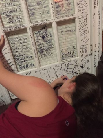 Spanish River senior Suzy Liss signs a door inside QQuest Live Escape Games. The walls and doors are covered with customers' signatures.