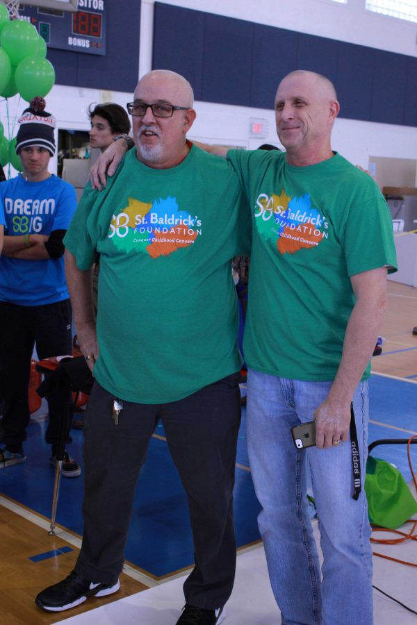 Math teacher Christopher Coombs (left) and school counselor Mark Carson pose for photos after shaving their heads.