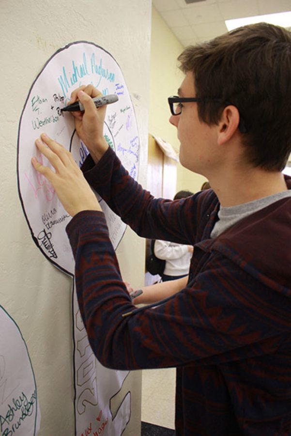 Band senior Philipp Popp signs his name to an academic key to success, pledging his commitment to the National Honor Societys Project Integrity campaign. NHS hosted the event in the cafeteria on Friday, Feb. 19, as part of the week-long initiative dedicated to bringing awareness to academic dishonesty.