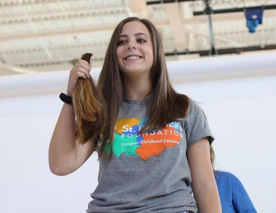 Communications sophomore Ariel Gordon smiles while holding up her donated hair.
