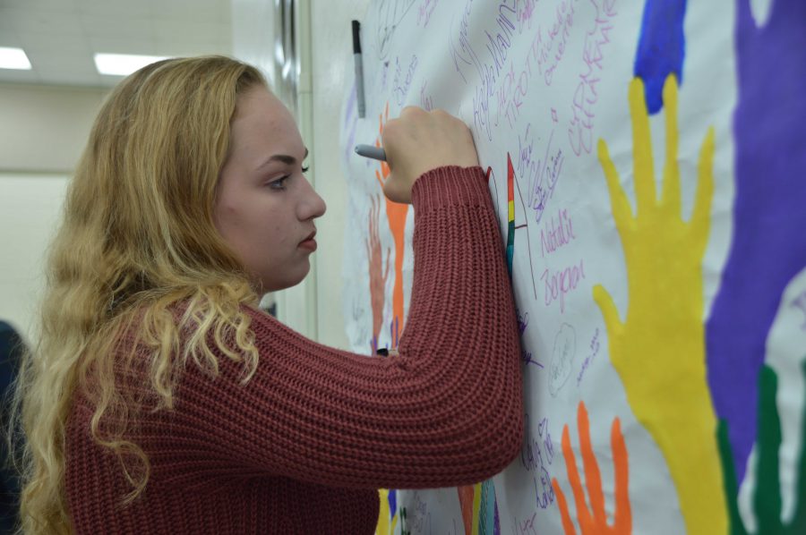 Dance sophomore Emily Sutterfield signs a decorative banner in solidarity for LGBTQ+ rights. April 15 is the international Day of Silence when students across the world refrain from speaking for 24 hours to raise awareness for the LGBTQ+ community. 
Today is whats called the Day of Silence and we decided that, as a school thats all about expression, it would be better to have a day to speak out in solidarity than to be silent, said communications junior Matthew Nadel. 
Students gathered in the cafeteria to sign petitions and statements regarding various issues that face the community. These included a pledge to stand up for LGBTQ+ students who are being discriminated against and also expressing interest in having Dreyfoos implement gender-neutral bathrooms. 