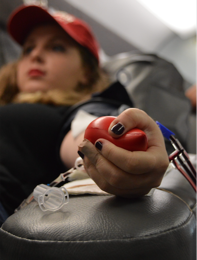Theatre senior Jillian Tone squeezes a stress ball to help the flow of blood as she donates to the blood drive. 