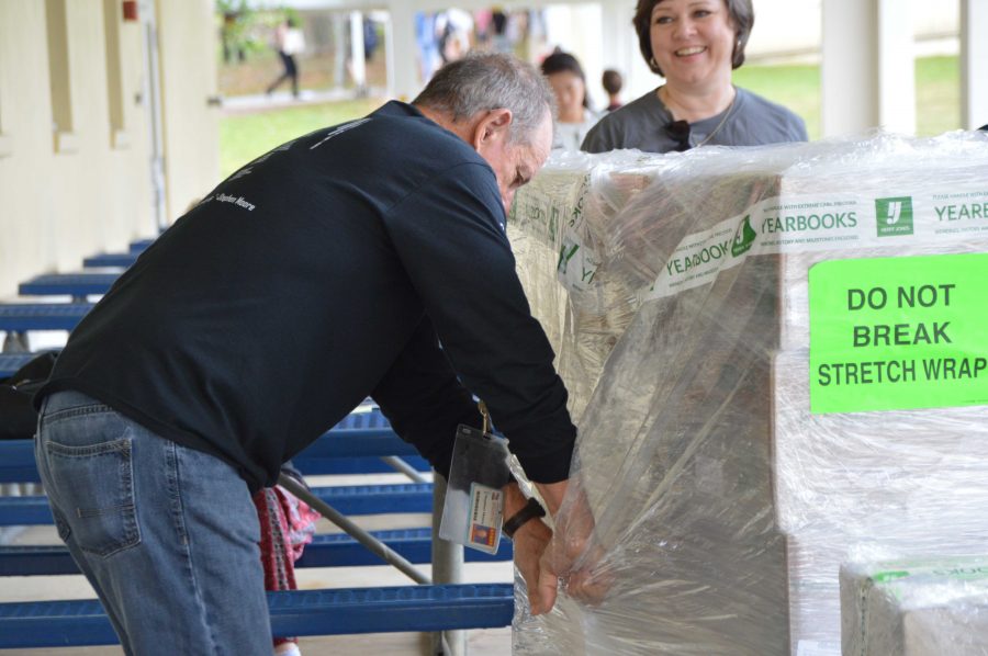 Marquee adviser Stephen Moore opens the packaging that holds the 2015-2016 yearbook. The Marquee staff has been working for over a year to produce the latest yearbook, Art. The book looks good. The class worked really hard on it and I hope everyone enjoys it, Mr. Moore said. Yearbooks can be picked up and purchased in the cafeteria starting April 27.