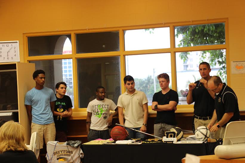 (L-R) Visual junior Aaron Nisbett, communications junior Elliot Hacker, vocal freshman Jaylen Thompson, band sophomore Adam Freedman, band junior Derrek Brown, social studies teacher and Basketball Coach Jeffery Stohr, and social studies teacher and Athletic Director Ross Vening recognize members of the basketball team for their accomplishments this season. 