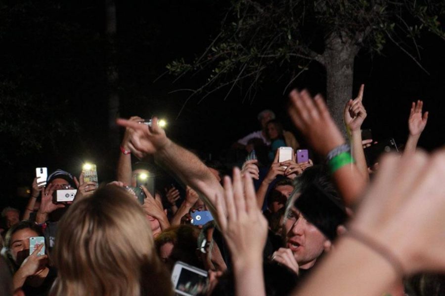 Concert attendees wave their hands in the air as Dan Smith, lead singer of Bastille comes into the audience.