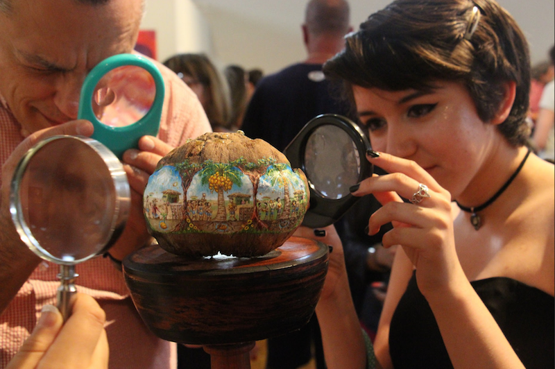 Visual senior Jailine Cano admires a piece by visual senior Palmer Crippen. The piece was made of a coconut, in which a story was painted in remarkably small detail. The details were so minuscule that one had to look through a microscope to grasp the whole story.