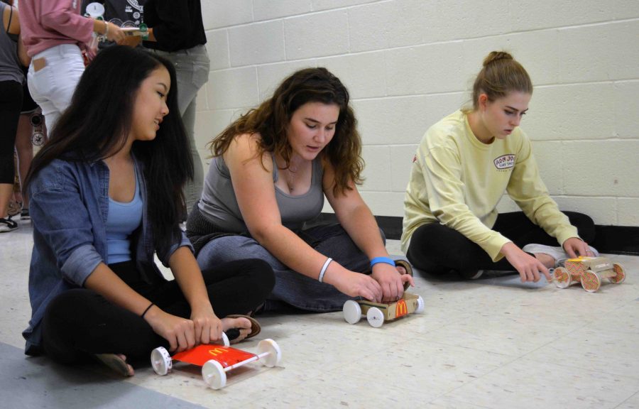 (L-R) Band junior Lihn Ton, communications junior Dylan Pollak, and dance junior Pia Kresse practice racing the cars they built for physics class using only a rubber band and McDonalds trash. The process of creating the car was tedious, but it was rewarding to see my hard work pay off when it [the car] actually worked, Ton said.