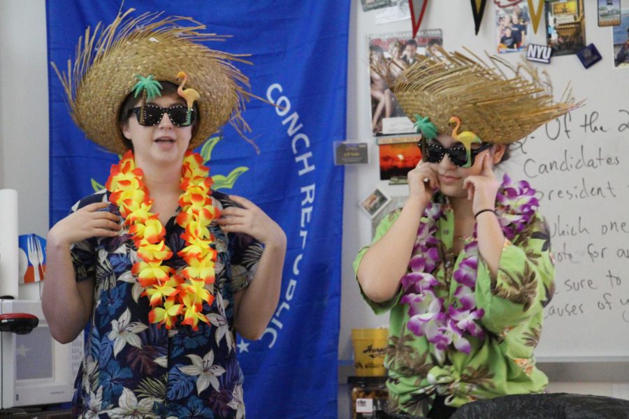 (L-R) Theatre seniors Bethany Hoffman and Emily D'Addio give a presentation in social studies teacher Jeffrey Stohr's AP Government and Economics class on Jimmy Buffett's company, Margaritaville. Students were asked to choose a major company or entrepreneur and present their research to their class to exemplify economics in the world. "We thought it'd be a fun idea to do something different and put our own flair to it. It just took a quick drive to a party store and $20 later, we were dressed as Parrotheads. Dressing up is my favorite thing to do. It's always fun to see the reactions people have to an outrageous getup," Hoffman said. Presentations will continue through next week.