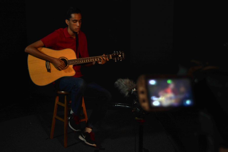 Theatre senior Keshin Martin plays and sings an original song while communications majors film him for his music video during lunch.  My music is very personal and it takes me forever to write, Martin said. This song actually took me about three months to complete because I had to balance songwriting with school work.