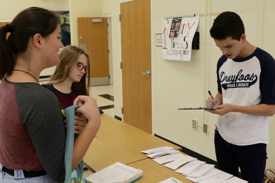 Communications+sophomore+Michael+Bole+sells+a+Dreyfoos+piano+sticker+as+part+of+a+Speech+and+Debate+fundraiser.+The+Speech+and+Debate+team+will+be+selling+stickers+every+day+at+lunch+in+the+cafeteria+to+raise+money+for+their+upcoming+tournaments.