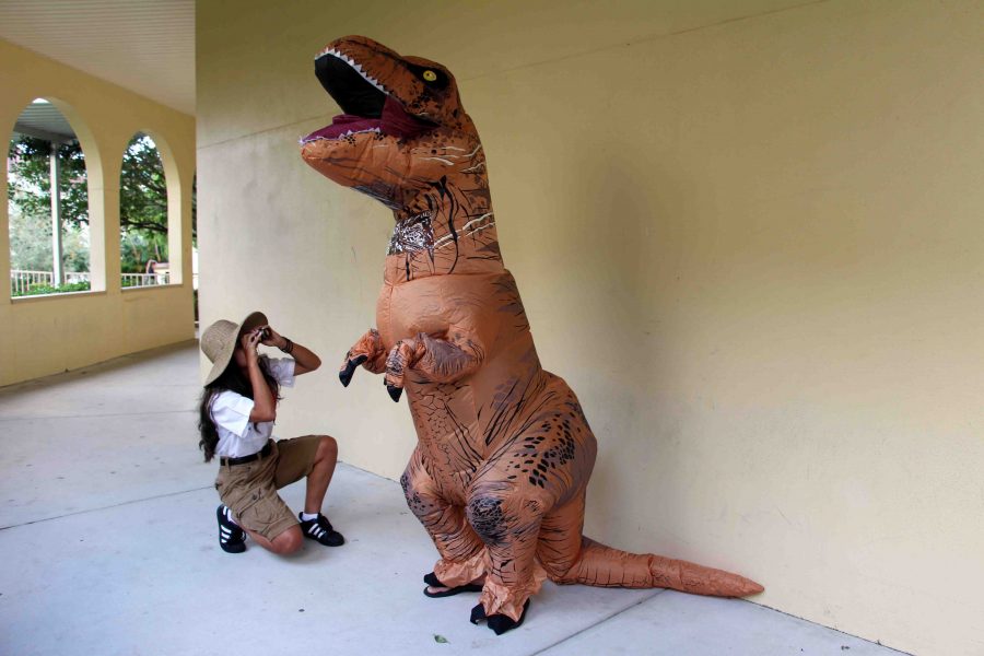 Visual senior Gleinys Martinez (left) stares up through binoculars at  communications senior Daniel Kaufman, clad in a dinosaur suit, on Safari Day.
Iconic. Ive never seen anyone dress up like this, Martinez said. This is prehistoric.