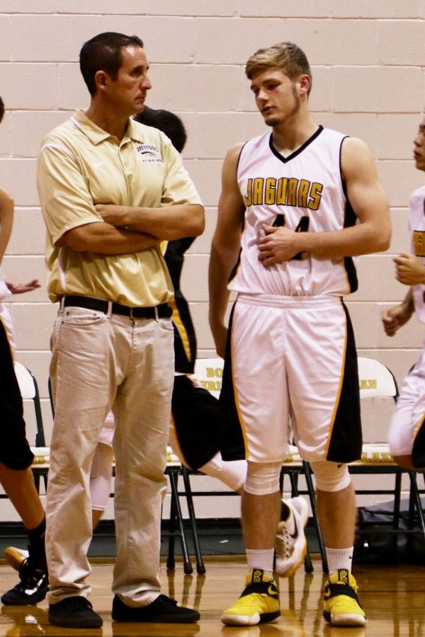 Starting forward and visual junior Aaron Crawford stands alongside basketball coach and history teacher Jeffrey Stohr at a basketball game prior to his season-ending injury.