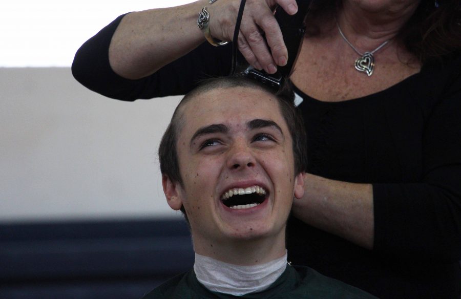 Communications junior Garret O’Donnell smiles as his head is shaved for St. Baldrick’s 