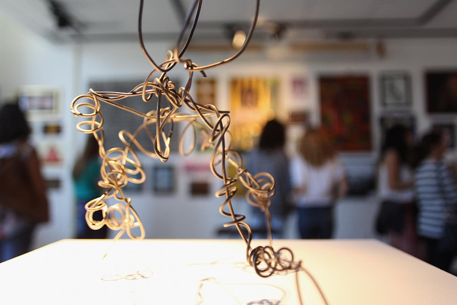 Placed on a white podium, a gold, metal-wire sculpture is featured, illuminated under the iridescent spotlight. The Visual Arts/Digital Media Spring Show featured a diverse range of art mediums from acrylic paint to charcoal, as well as a variety of subjects from fruit to portraits. Spectators were able to see the culmination of hard work by visual and digital media students leading up to the art gallery on April 11, through both upstairs and downstairs exhibit galleries found in Building 9.