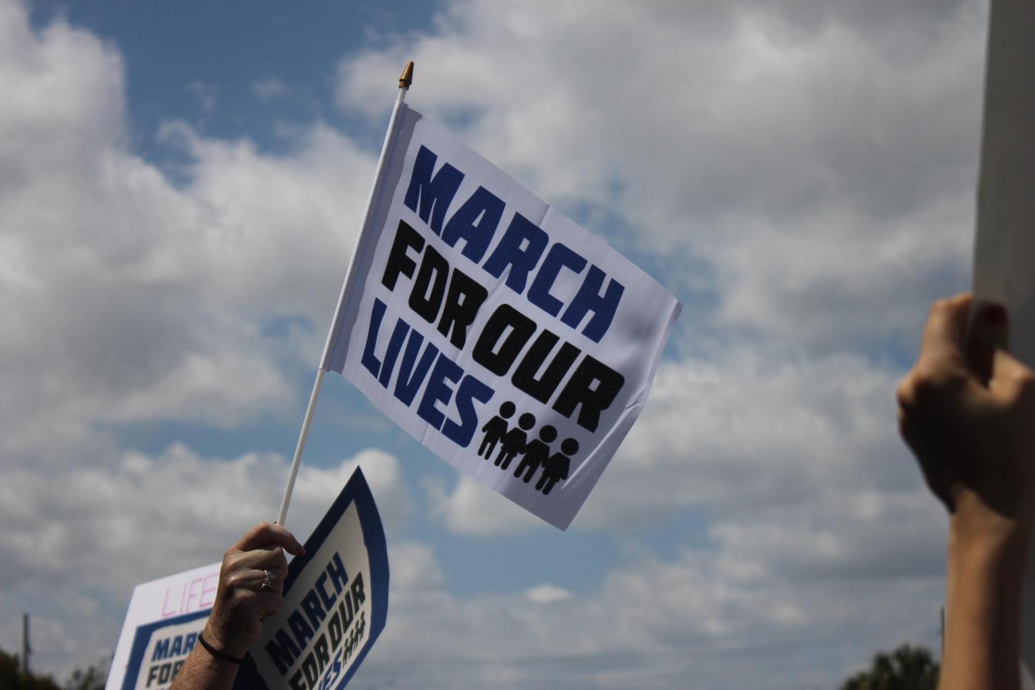 An activist at the West Palm Beach March for Our Lives stands alongside thousands of others, all with signs and flags to call attention to the excessive gun violence in the U.S. Students behind the Never Again movement were able to raise millions of dollars, and used the donations to organize events worldwide. Flags like the one pictured above could be purchased at the march, and all funds were to support the cause.
