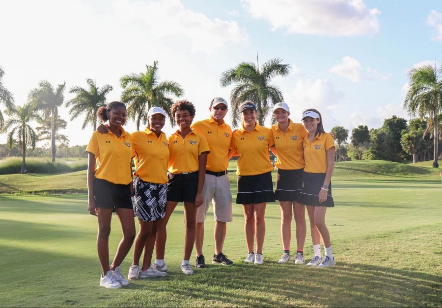 The girls’ golf team stands unified in black and yellow having finished their match on Oct. 3 at Okeeheelee Park. Matches like this are helping the girls prepare for FHSAA District Girls’ Golf Tournament at the end of the season. (L-R) Visual junior Myah Clemons, piano freshman Janise Tucker, visual sophomore Kailyn Bryant, girls’ golf coach and School Counselor Mark Carson, communications senior Lilly Randolph, theatre sophomore Emma Troast, and communications freshman Marion Randolph hope for the best at the upcoming matches. 
