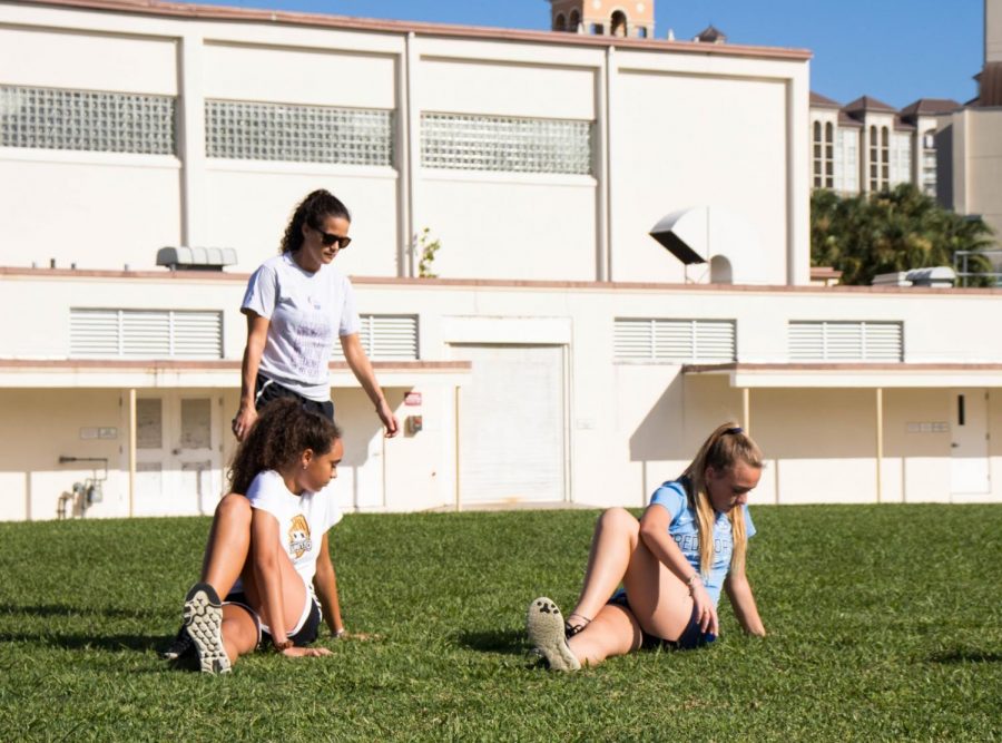 Girls’ soccer coach and media specialist Sarah Garcia stands and watches as prospective players for this year’s girls’ soccer team stretch.