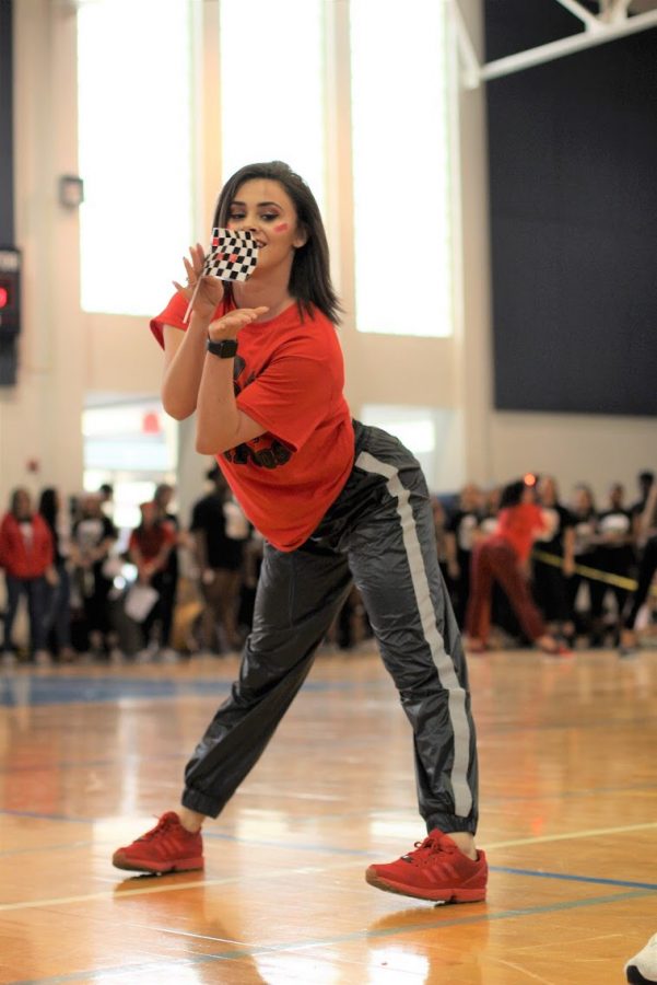 For the second time in the Pep Rally, dance junior Alexa Olivier prepares to toss a checkered flag across the gym floor. Following a music mishap during their first performance, the juniors repeated their dance before winning the event.