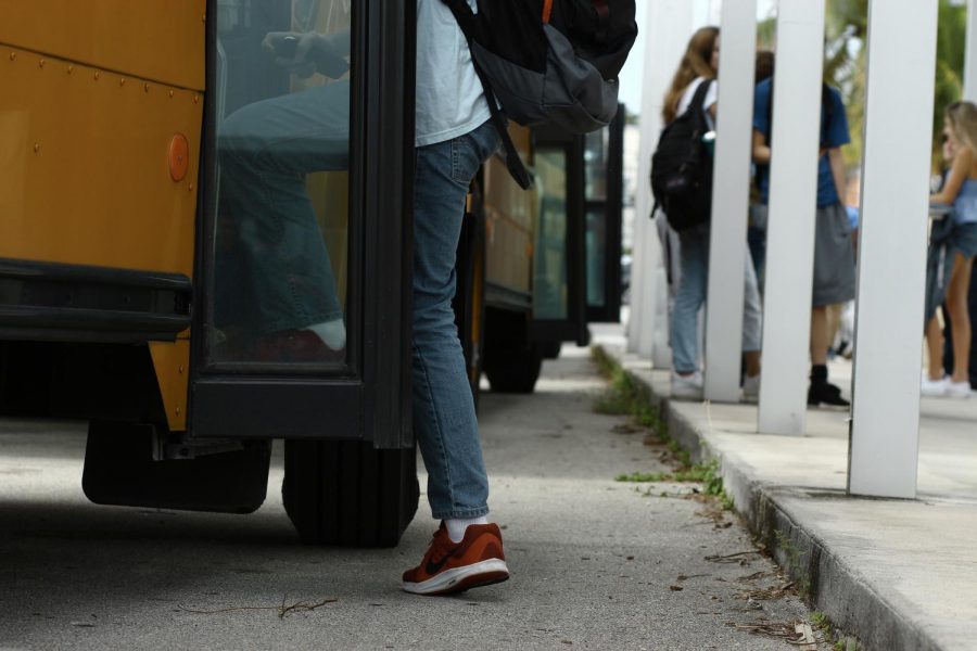 A students boards a Dreyfoos school bus in the afternoon, while peers await their buses beneath a walkway cover. Like many other Dreyfoos students, Communications senior Kristina Robinette completely depends on school transportation. “If something happens, where [the bus is] totally late, theres nothing I personally can do to make a difference for my life. There are so many times Ive had to text my [boss] and say, ‘Hey, I dont know if Im going to make it on time.’ I have a corporate job. Its not a family business, [so] I could get fired because of the bus system.”
