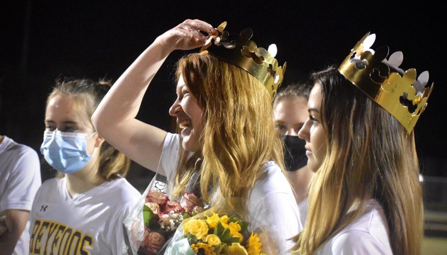 Senior%2C+left+midfield%2C+Katelyn+Carter+smiles+as+she+is+given+flowers+and+a+crown+by+her+teammates.+Players+surround+her+and+celebrate+senior+night+while+following++COVID-19+guidelines.