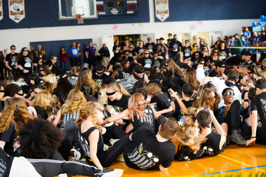 The class of 2020 piles on top of one another before stacking into the bleachers above, the final cue to begin the event.