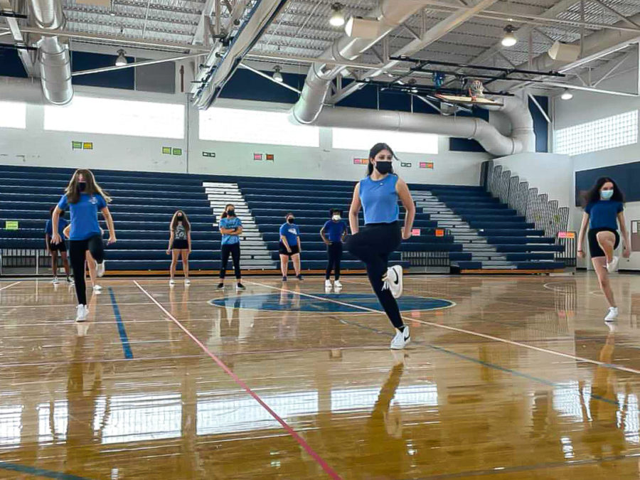 Dance freshmen Savannah Ehrlich, Isabella Passos, and Anna-Sofia Machado stand centered on the gym floor, practicing their routine before the final take for the freshman pep rally dance.