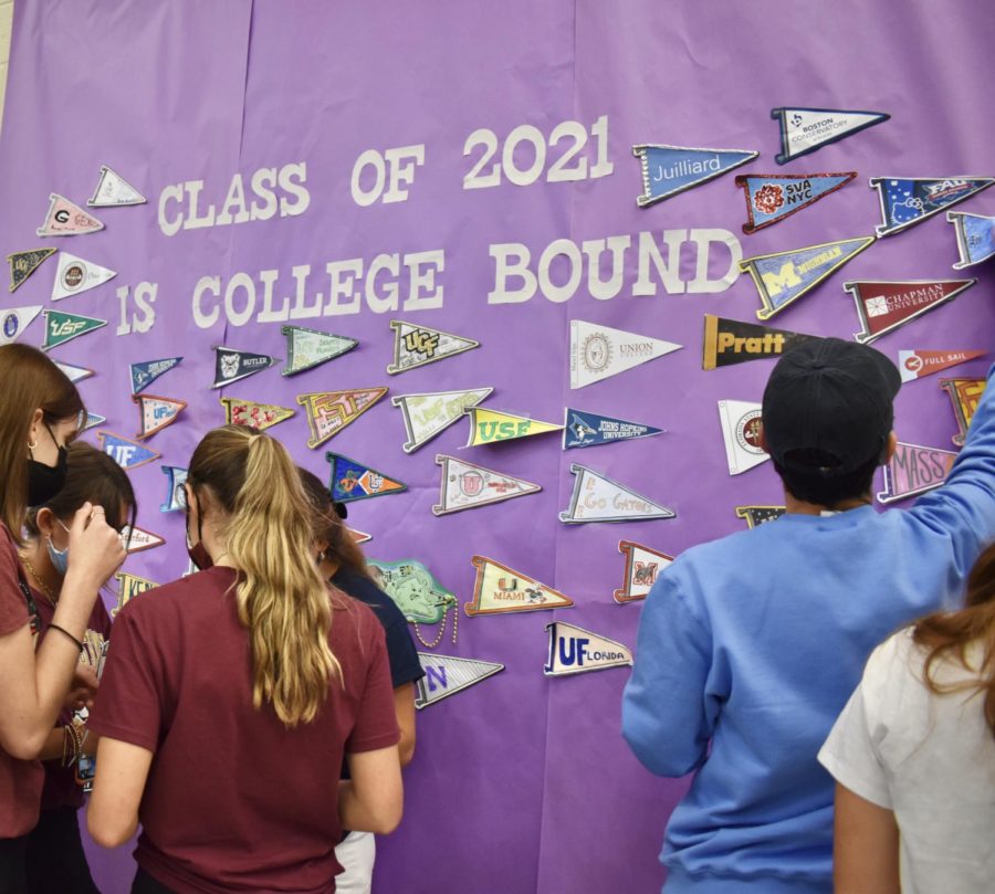 Students gather to hang pennants on the cafeteria wall. Seniors were asked to decorate their pennants with their college logos prior, though decorating materials were available at the event. 