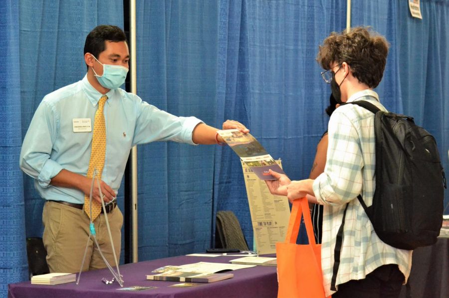 An admissions officer from Sewanee University hands visual sophomore Tyler Wetter a brochure detailing the different programs and opportunities offered. Students were given bags from Revolution Prep Tutoring to gather brochures, contact information, school merchandise, and other resources from schools they talked to.
