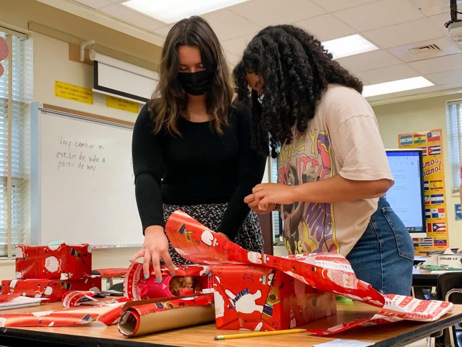 Visual juniors Arianna Sanchez and Natalie Alcover Carrasqui wrap gifts collected by the Spanish Honor Society as part of their holiday toy drive. The toys will be gifted to elementary school students alongside books the National English Honor Society donated, and each of the toys were purchased based on what the sponsored students requested on their Christmas lists. “I think it’s really nice to just give kids who aren’t fortunate enough to open a Christmas present (...) something to look forward to, and just give them that little magic miracle,” Sanchez said.