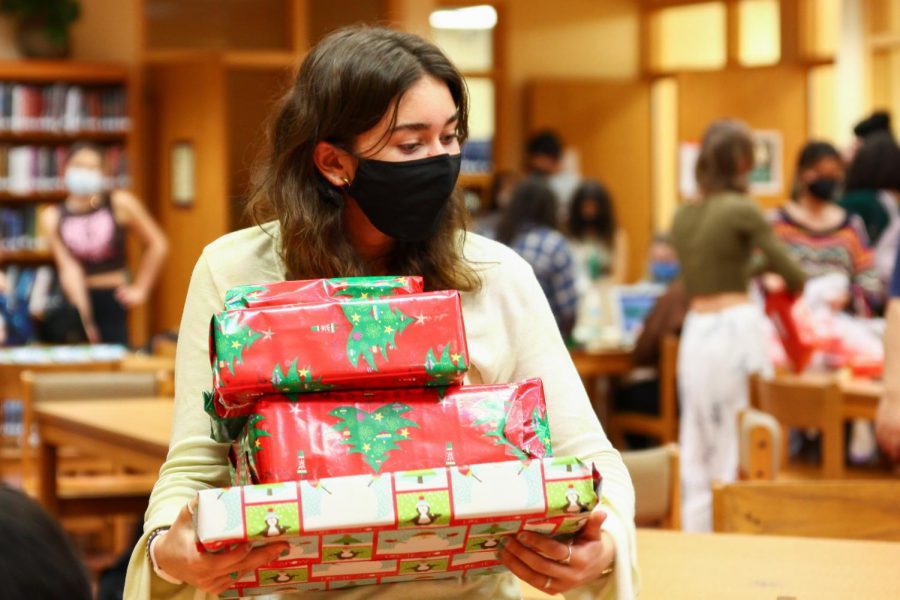Carrying a stack of freshly wrapped presents, digital media sophomore Giada Robinson goes to place her gifts in a collection bag. Students in Artists Reaching Out to Society (A.R.T.S.) Club worked together to wrap presents for the annual Jefferson Jubilee. “Im so enthused to be a part of this environment and this cause,” Robinson said. “Im really just looking forward to helping out and making a holiday special.”