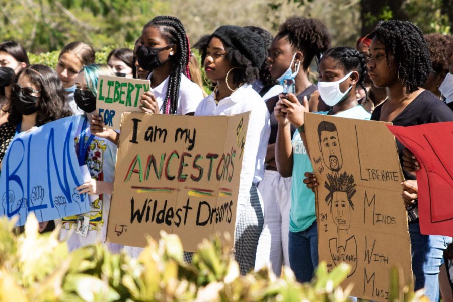 Listening to communications sophomore Josiah Manners’ speech, theatre sophomore Lillian Jones holds a sign that says “I am my ancestors wildest dreams.” Students and staff held similar signs as they gathered in front of the school and marched around campus. “I feel empowered,” Jones said. “I have never done this at any of my schools before, and I feel very unified.”