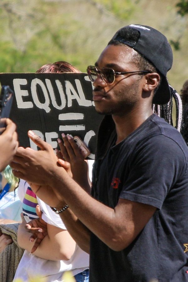 Standing in the crowd of students and faculty, visual junior Anthony Maynard claps in support of communications sophomore Josiah Manners’ speech, read at the end of the March on Dreyfoos. Photo Caption by Anna Jones.
