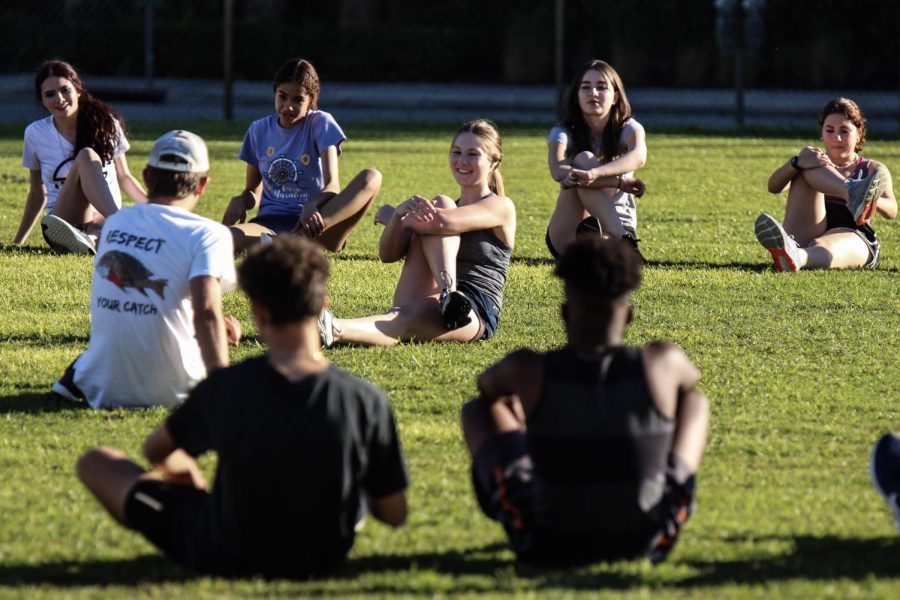 At the beginning of practice, vocal senior Erin Swabek helps lead the team in stretching exercises as one of her duties as a team captain on the Track Team. 