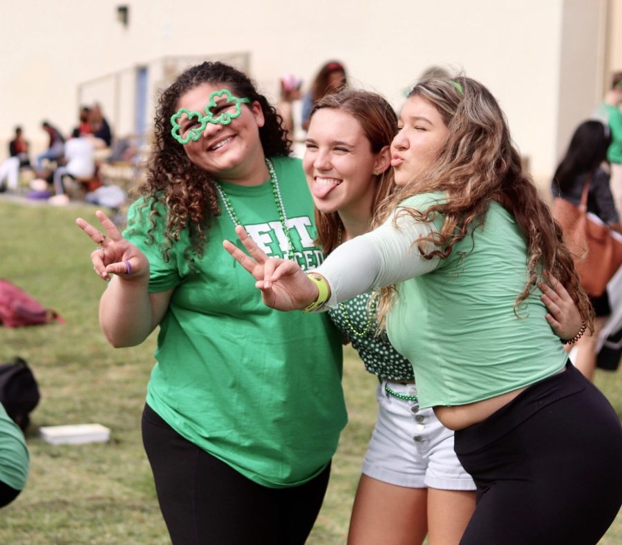 Theatre senior Kaytlin Sanchez and vocal seniors Lillian Critchett and Marbella Deininger pose on the field during the 2020 Spirit Week. For Holidays Day, sophomores can adorn bead necklaces, green shirts, and clover glasses.

